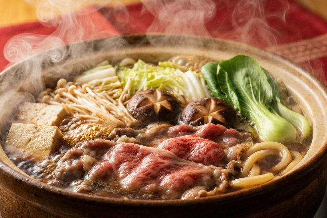 湯気が立ち上る熱々の鍋料理のクローズアップ。シズル感たっぷりで食欲をそそる。