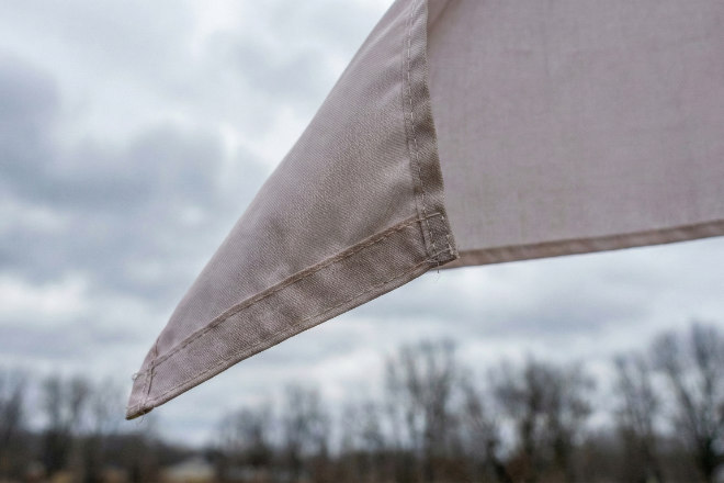 強風になびくのぼり旗の端のアップ。縫製がしっかりしており、丈夫であることを示す。