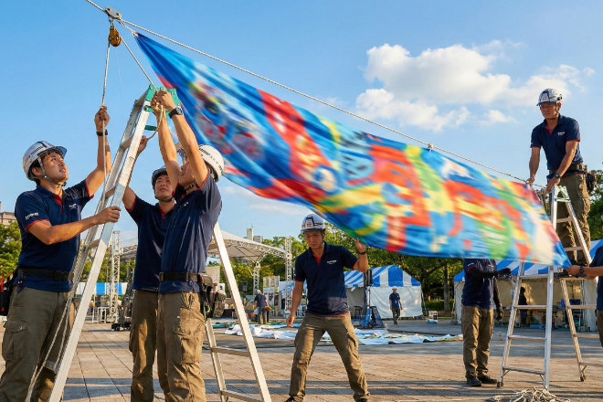 青空の下、イベント会場で横断幕を取り付ける日本人スタッフたち