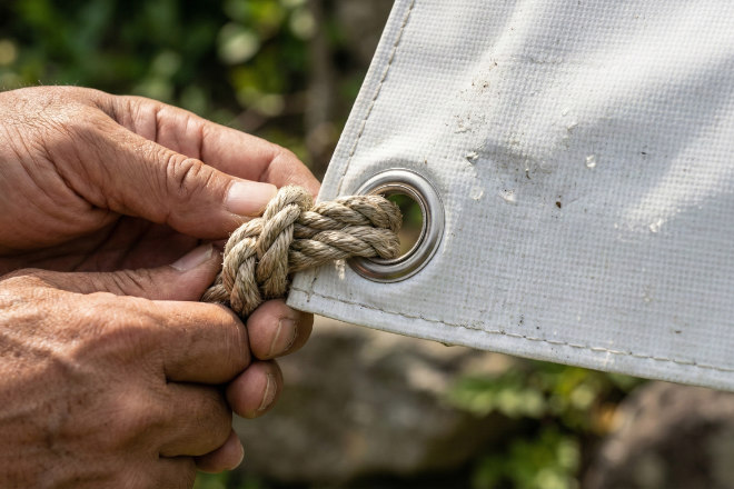 横断幕のハトメ部分とロープを結ぶ手元のクローズアップ